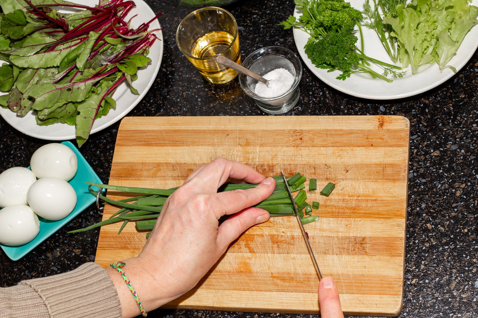 Close-up of hands chopping herbs on a cutting board